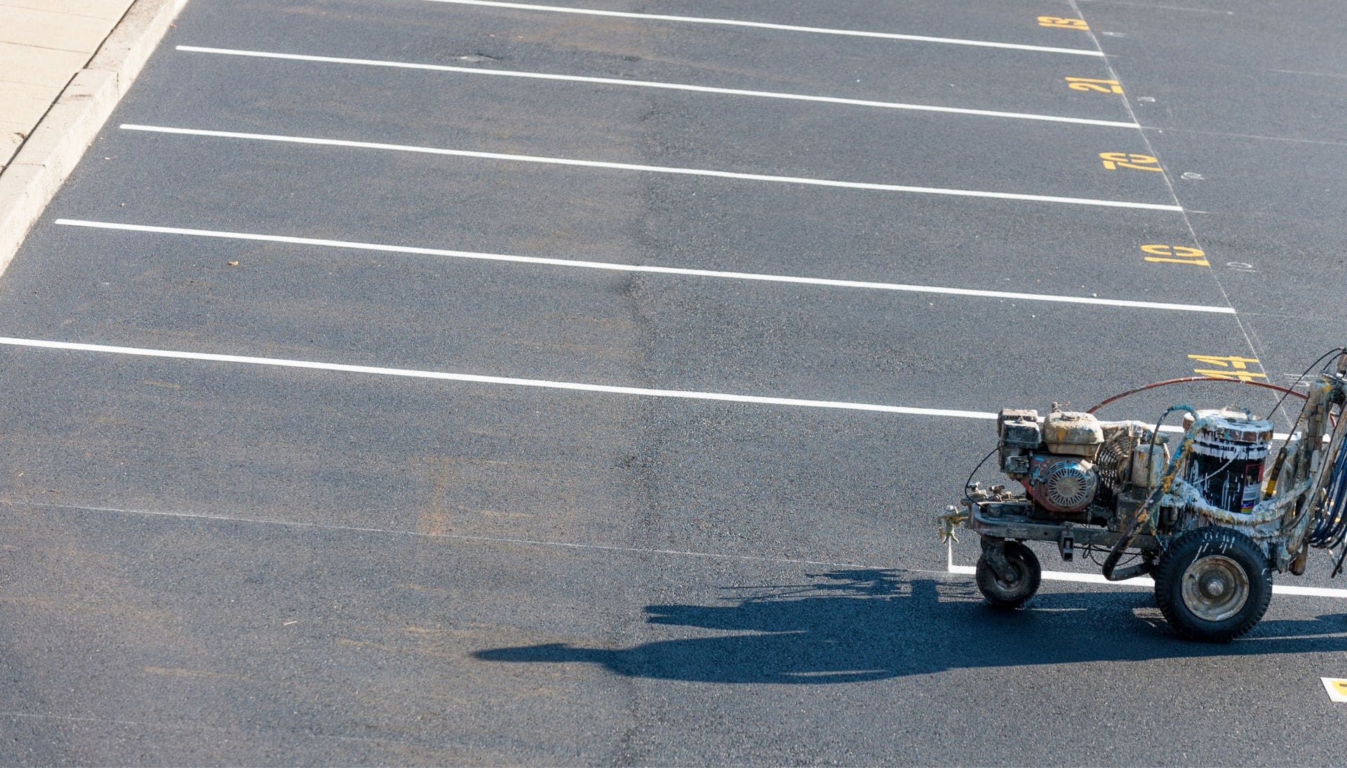 A parking lot striping machine is used by an asphalt contractor in Akron, OH to create parking spaces.