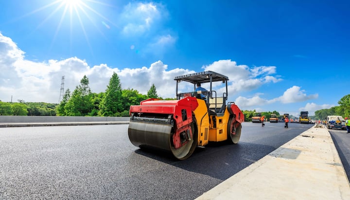 An asphalt contractor in Akron, OH operates a large commercial-grade roller.