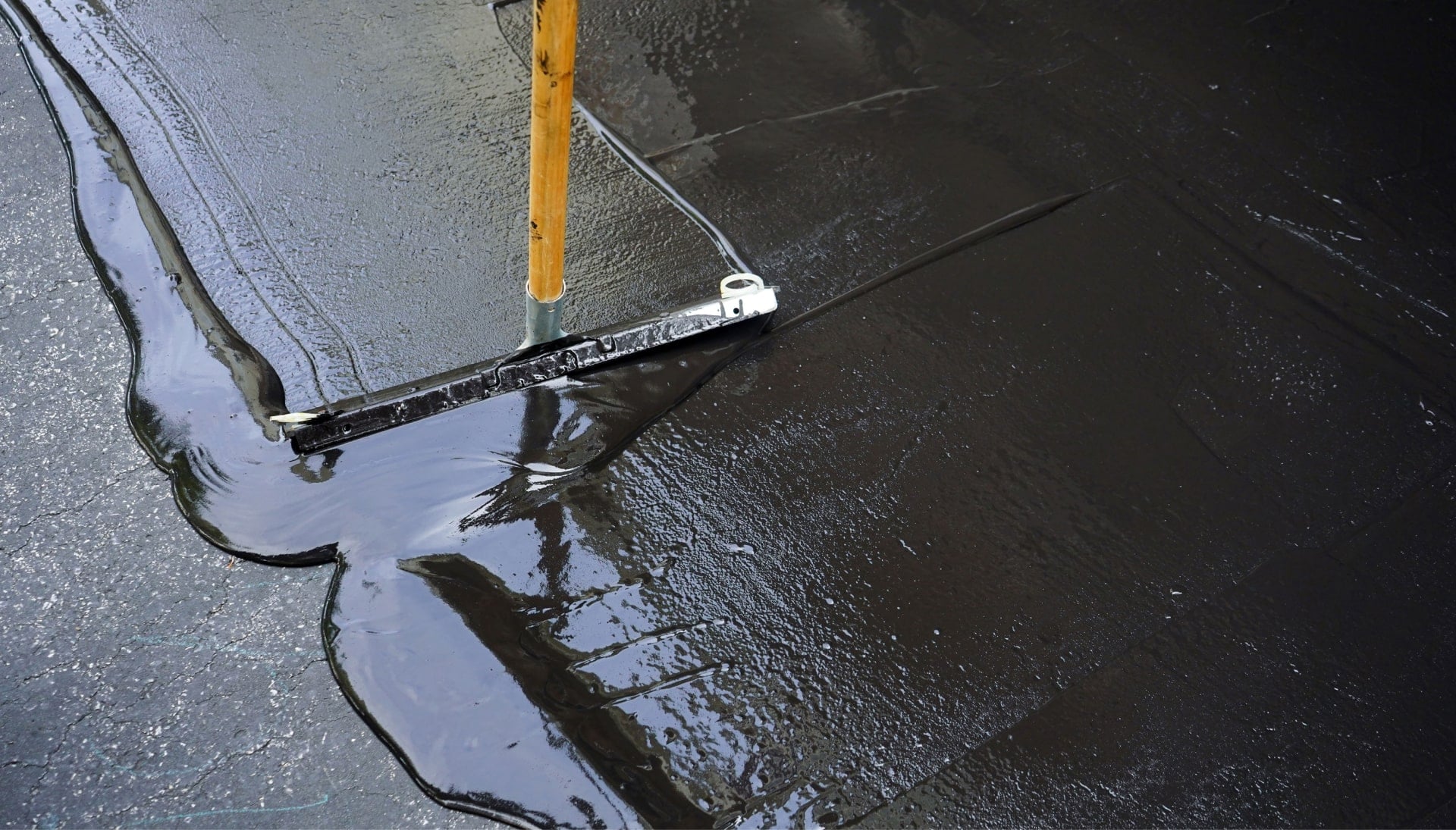 A squeegee is used for asphalt sealcoating in Akron, OH.